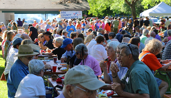 Wide photo of hundreds of BBQ attendees eating and enojying a good time.